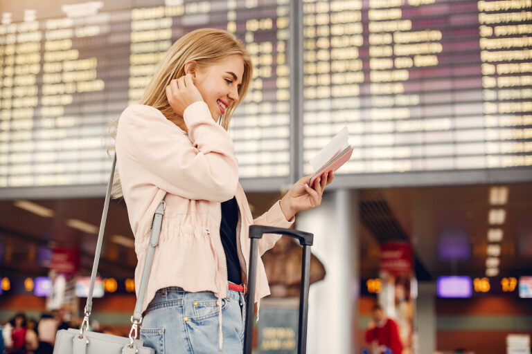 donna in aeroporto con tabellone voli nello sfondo